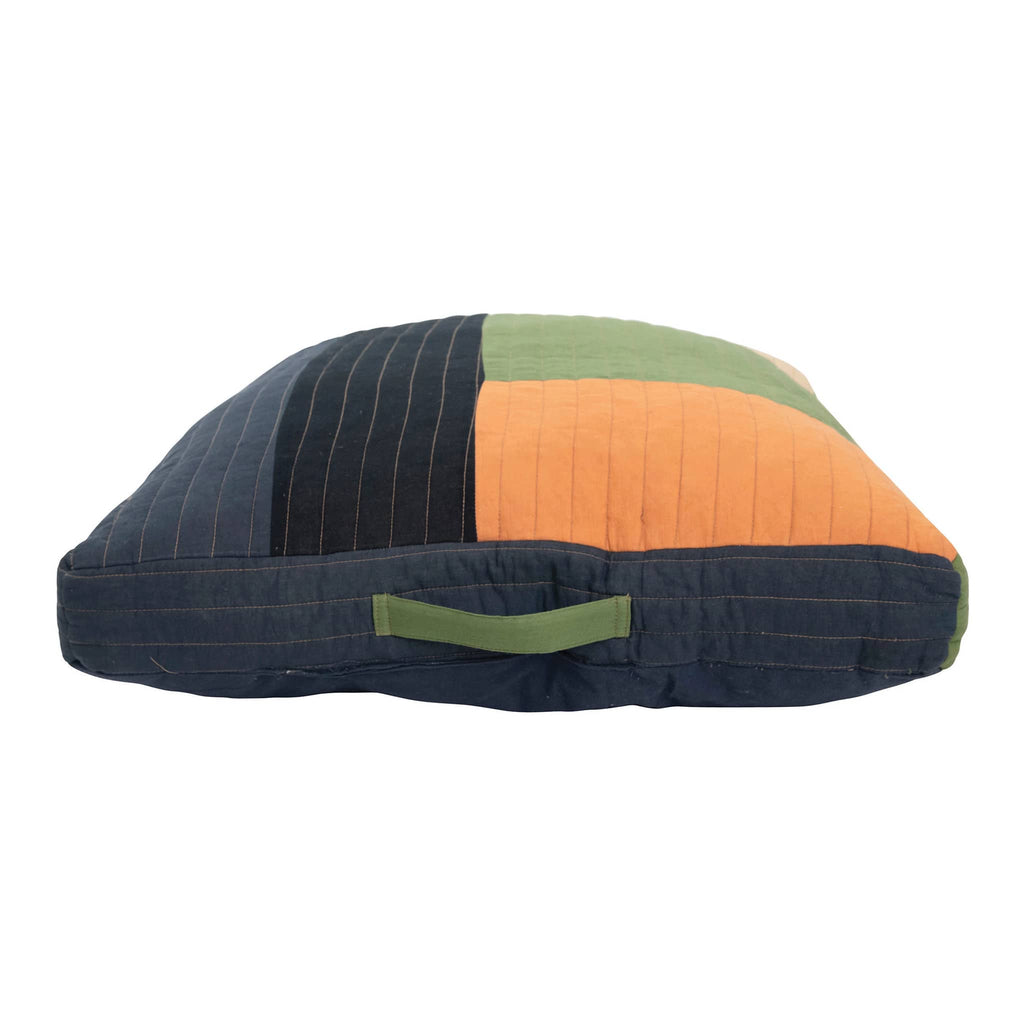 Colorful quilted floor pillow with a handle on a white background.