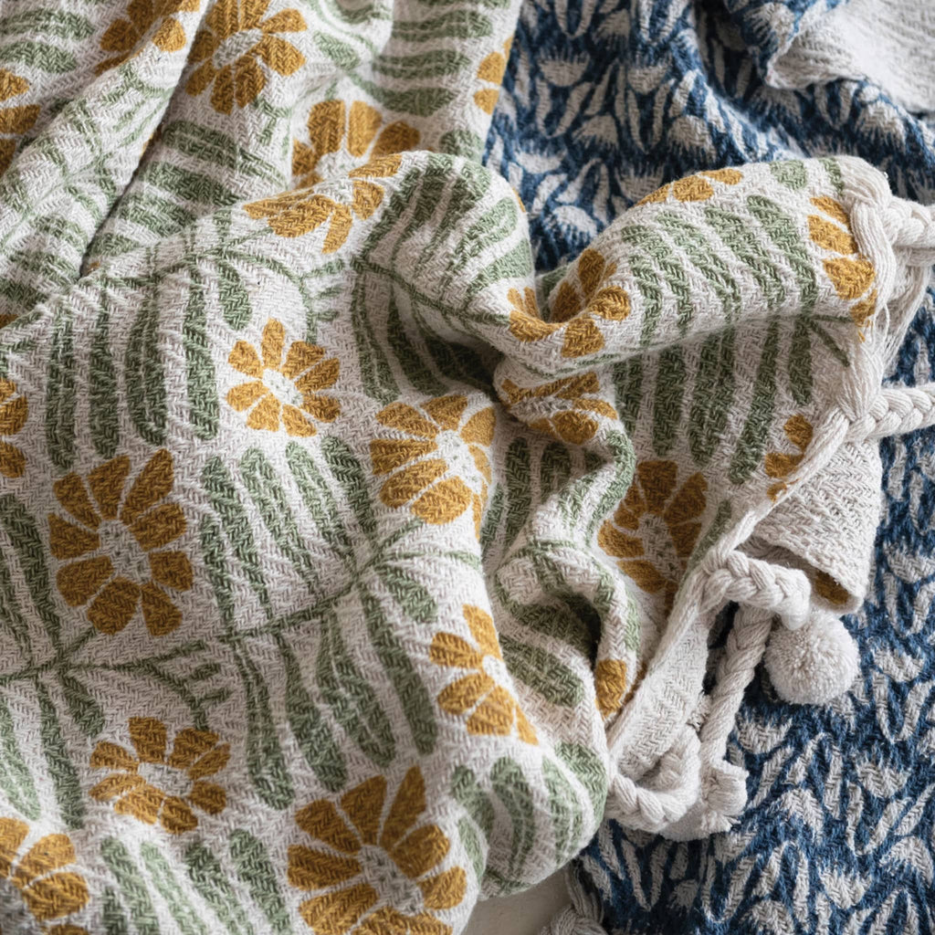 Creative Co-op woven recycled cotton blend mustard and sage floral print throw with braided pompom tassels, detail to show texture.