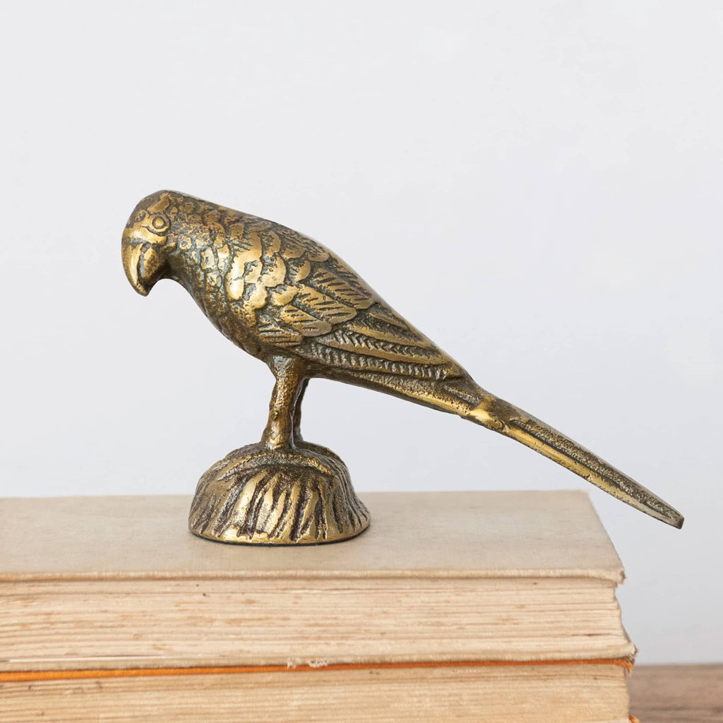 Creative Co-op cast aluminum bird with antique gold finish, side view on books.