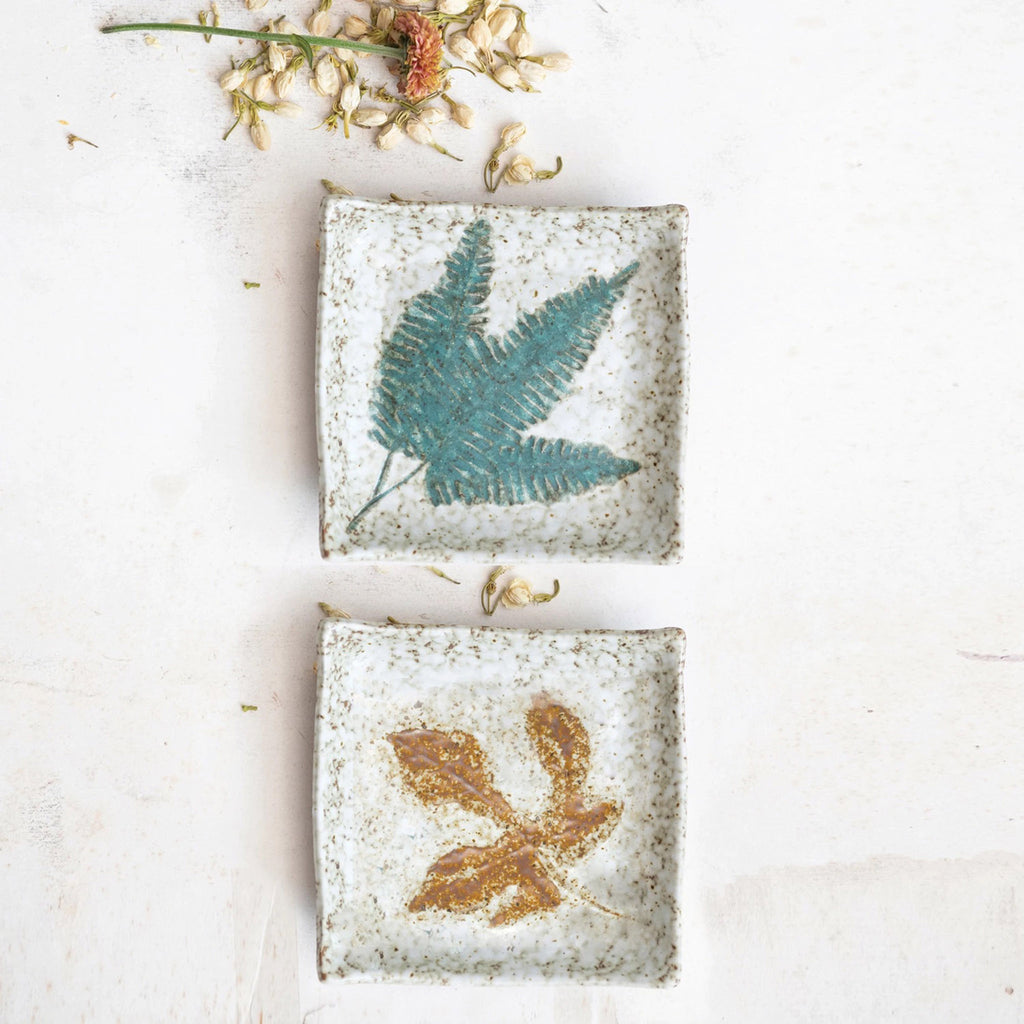 Creative Co-op Reactive Glazed Stoneware Plate with embossed leaf pattern in rust or green, with dried flowers.
