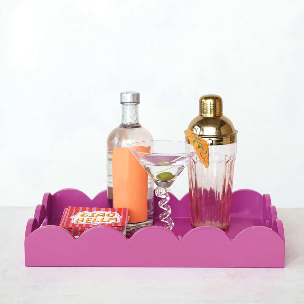 Creative Co-op MDF fuchsia lacquered rectangular scalloped serving tray, front view with a cocktail shaker, martini glass, cocktail napkins and a bottle.