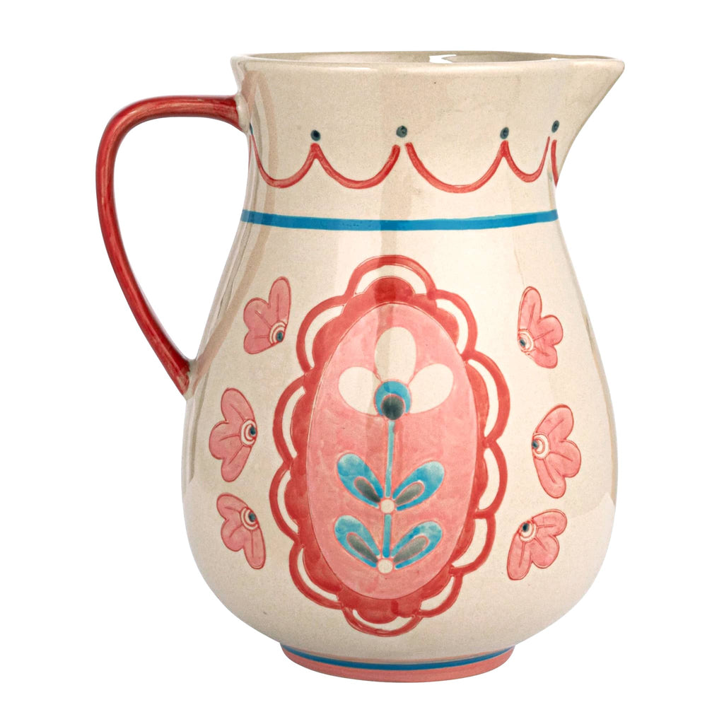 Creative Co-op Hand-Painted Floral Stoneware Pitcher with red handle on the left.