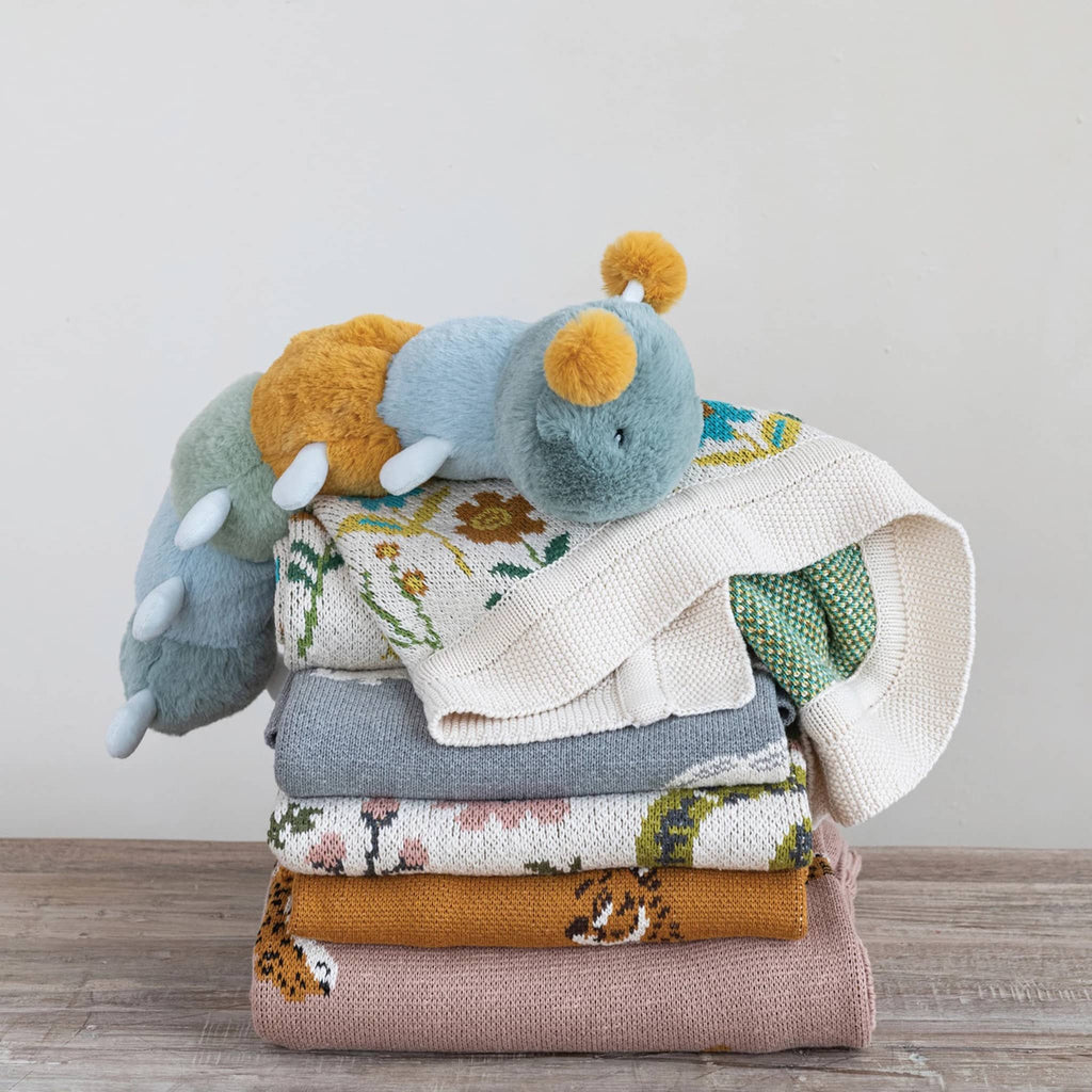 Creative Co-op Cheetah Cotton Knit Baby Blanket, shown in a stack with other blankets.