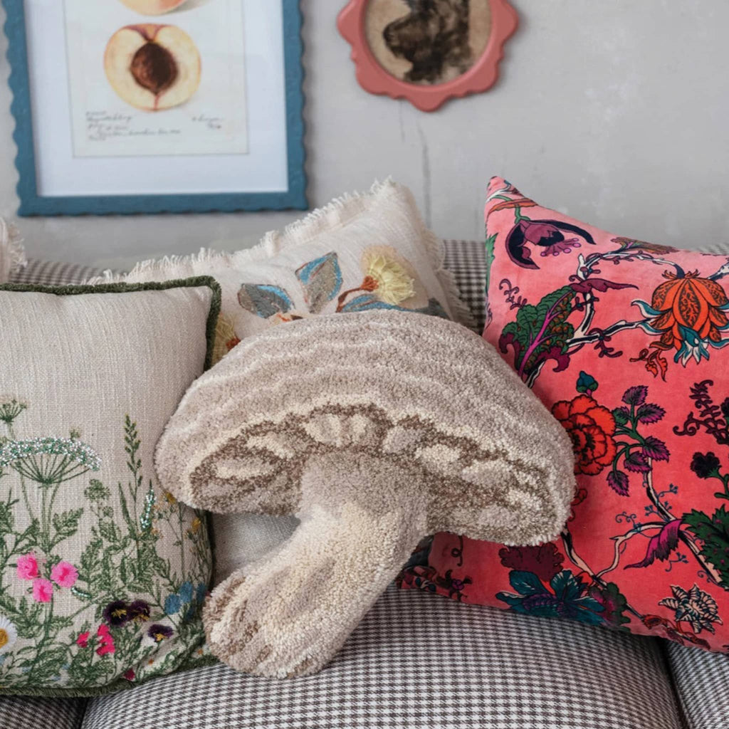 Wool tufted mushroom-shaped throw pillow in shades of brown on a sofa with other brightly colored throw pillows.