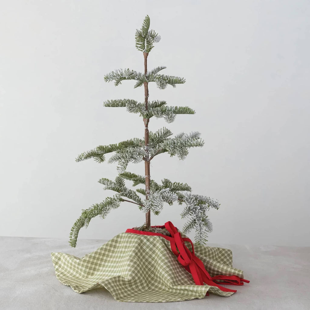 Small potted Christmas tree with green plaid tree skirt, on a light gray background.