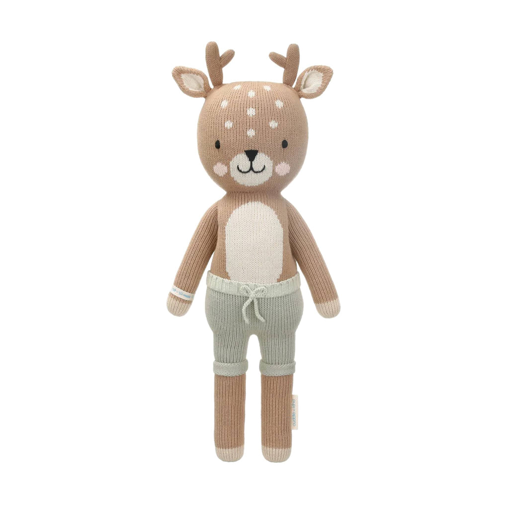 Knitted deer toy with sage green shorts, on a white background.