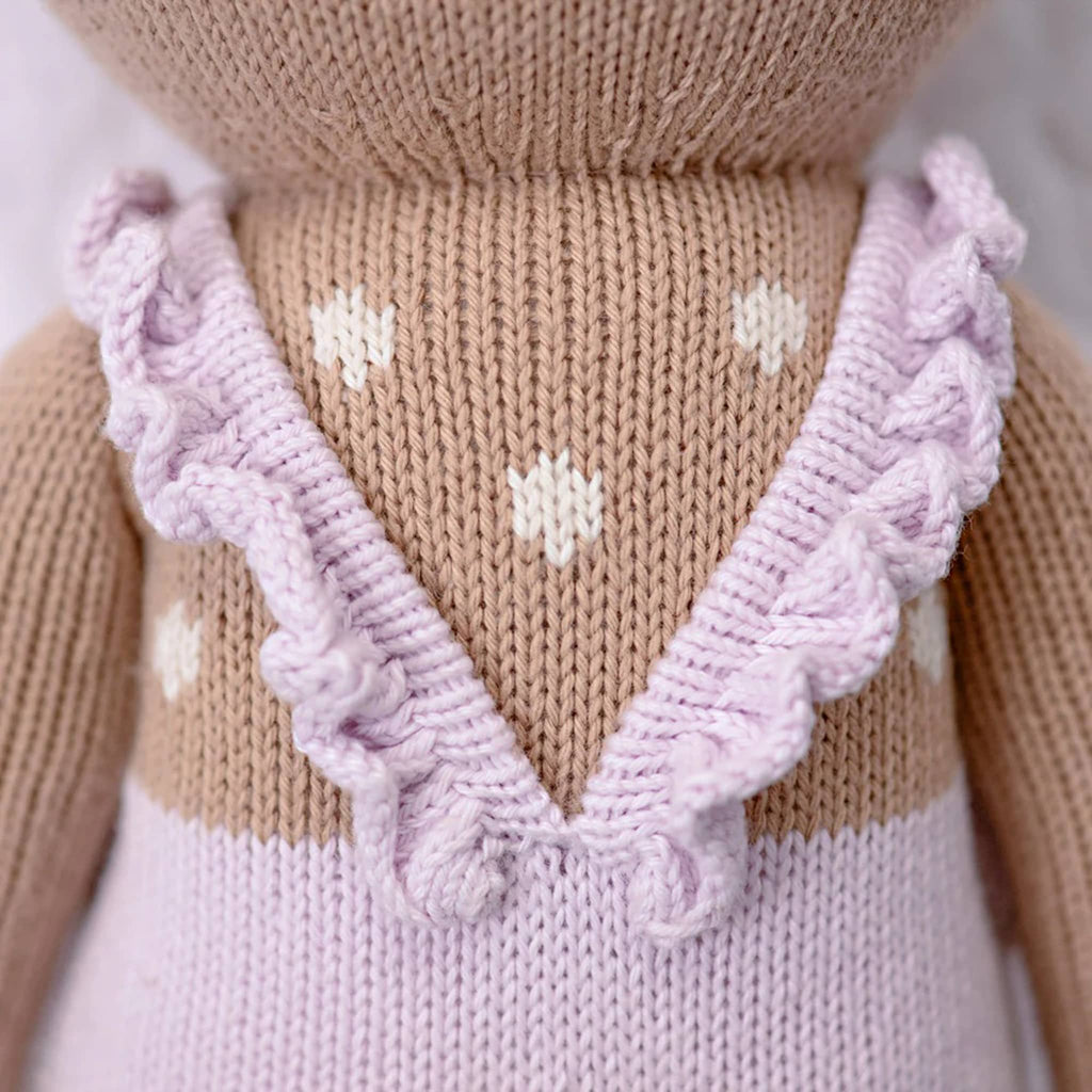 Close-up of a knitted garment with a V-neck and white dots on a tan background.
