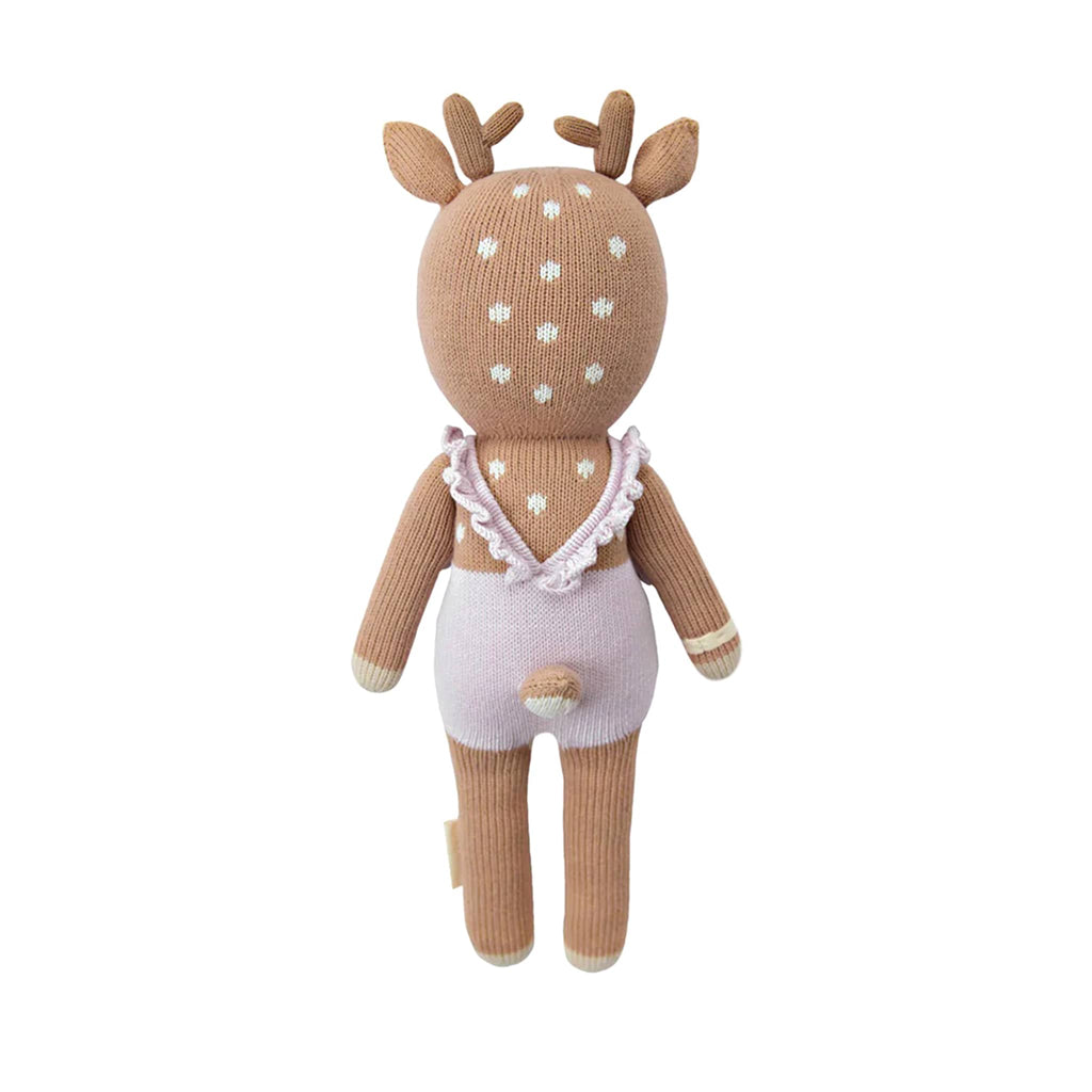 Knitted deer toy with a lilac ruffled dress on, back view, on a white background.
