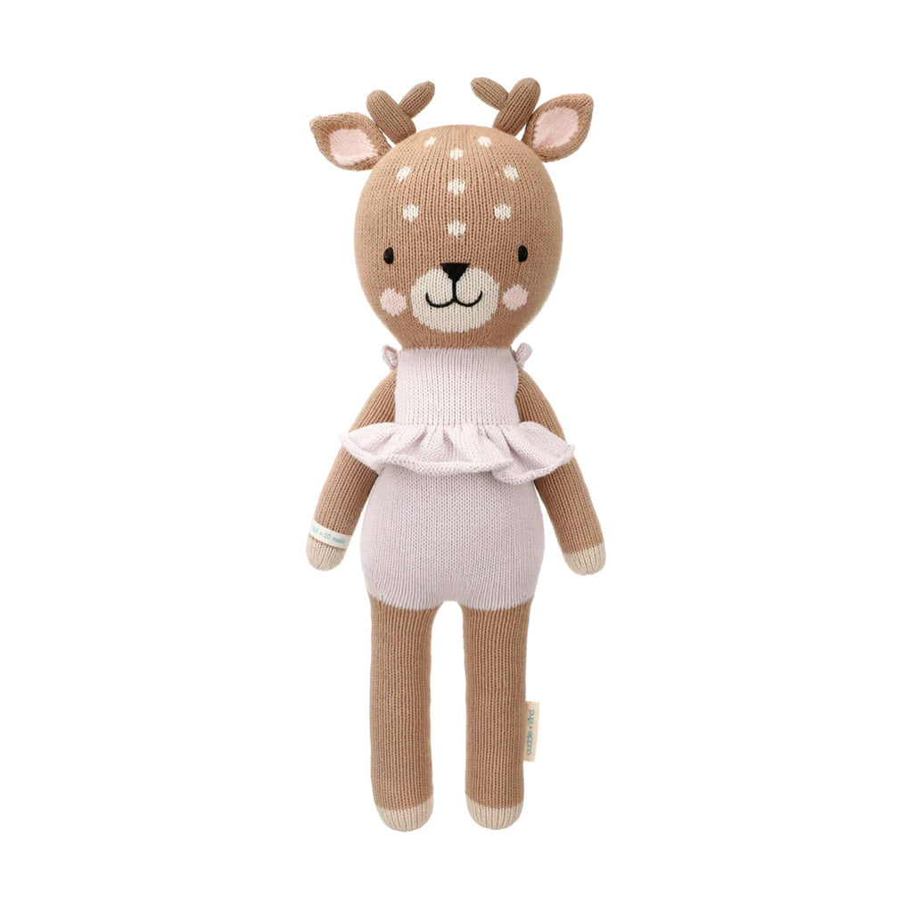 Knitted deer toy with a lilac ruffled dress on a white background.