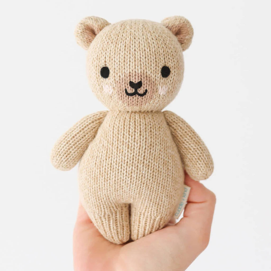 Cuddle and Kind Baby Honey Bear hand knit doll, front view in adult hand for scale.