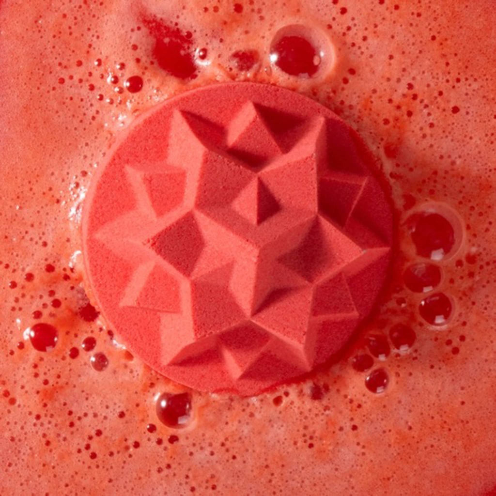 Red star-shaped bath fizzer with bubbles on a red background.