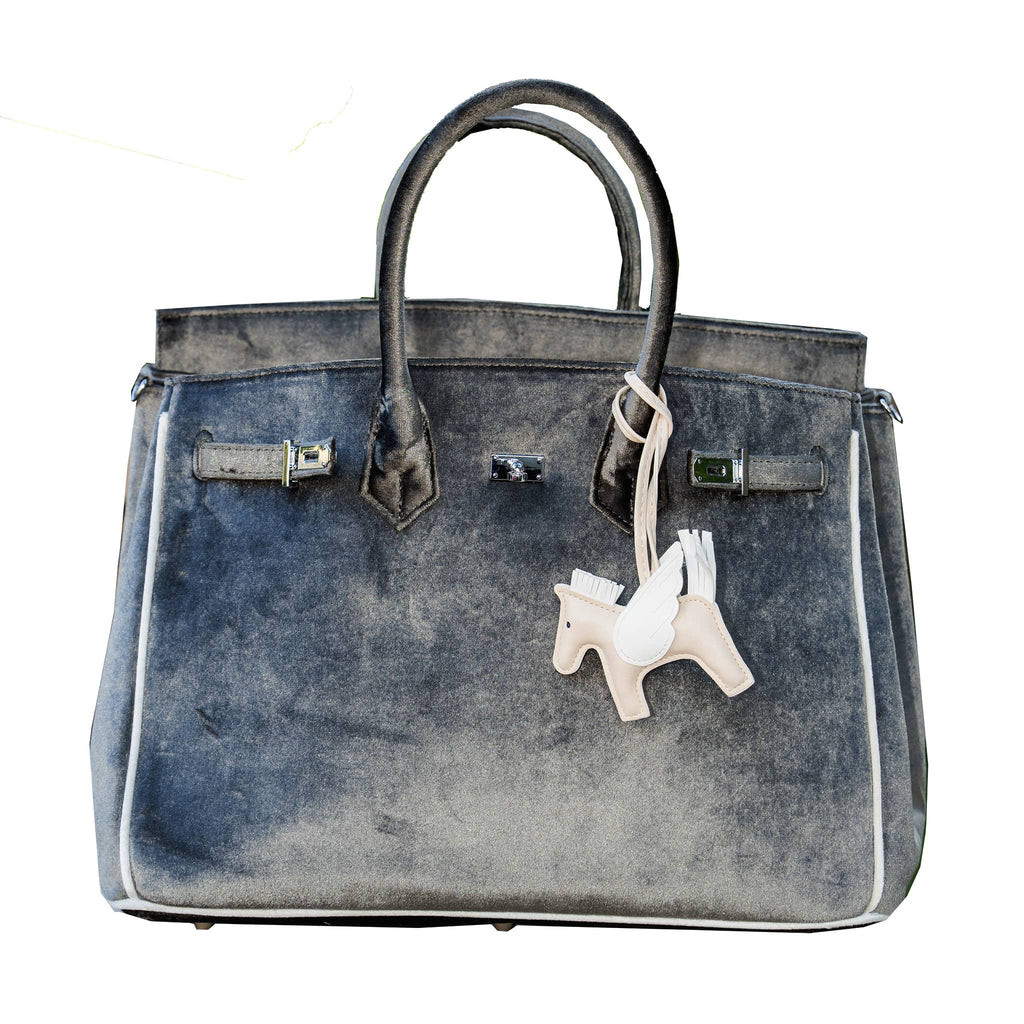 Charcoal gray velvet handbag with a beige and white horse charm on a white background.