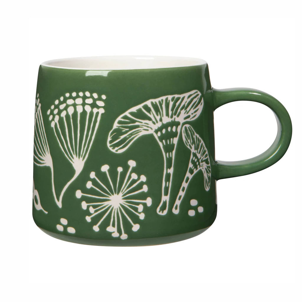 Green mug with white floral and fungi wax-resist patterns on a white background.