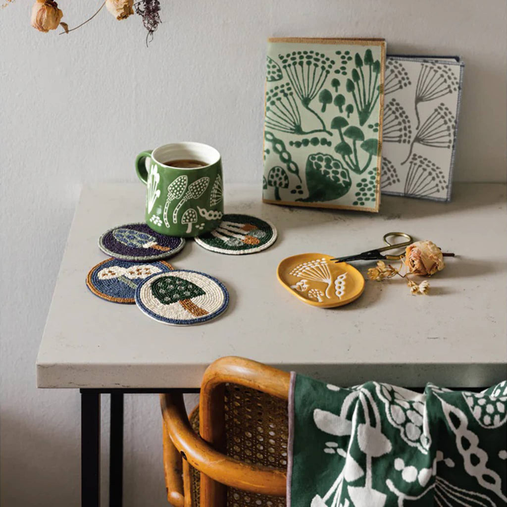 Table with ceramic coasters, a mug, and decorative items with green and white patterns.