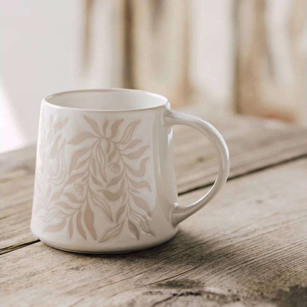 Danica Driftwood Berryvine Stoneware Mug with beige leaf print on a white backdrop, handle on right, on wood surface.