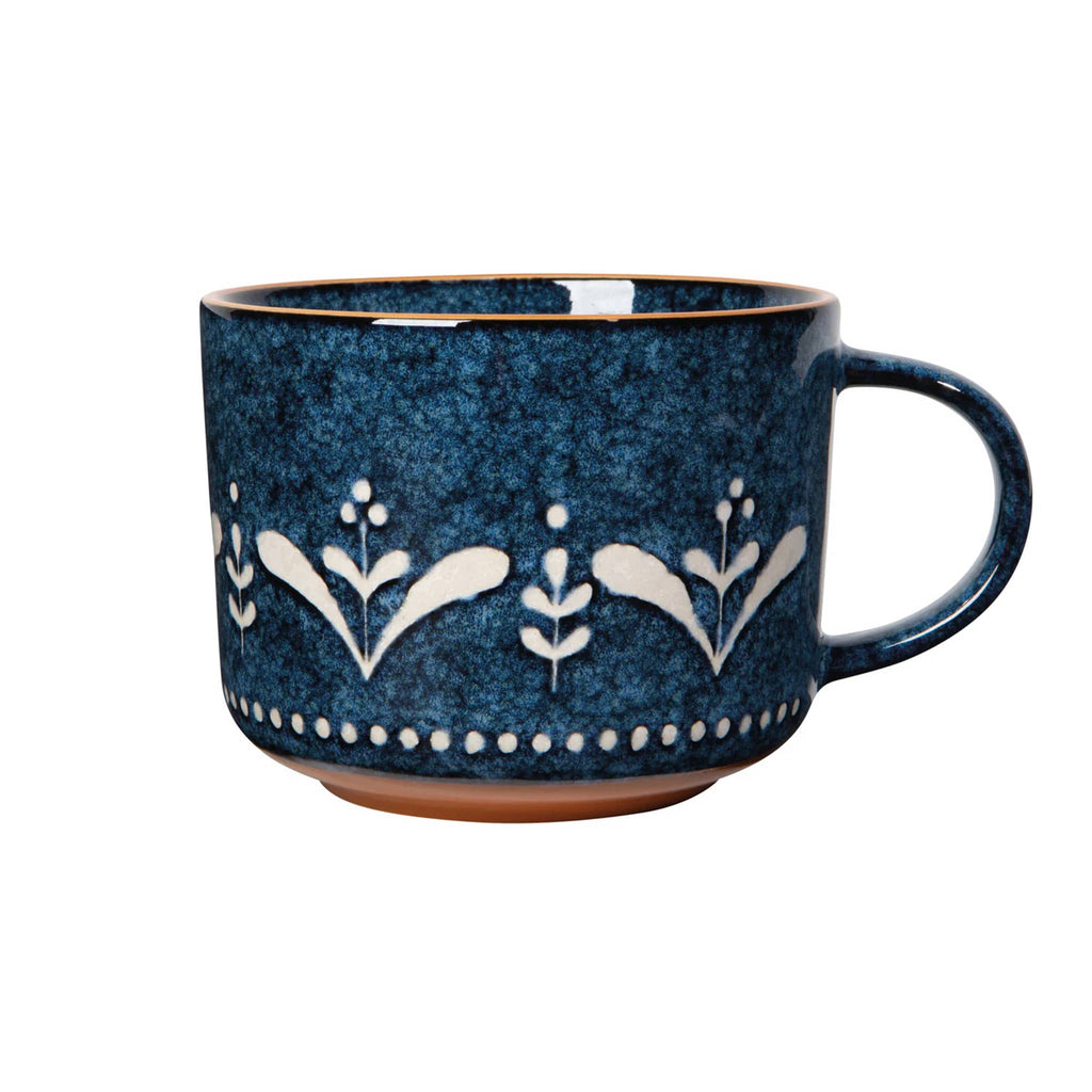 Blue ceramic mug with white floral patterns on a white background.