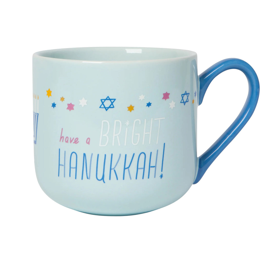 Danica Bright Hanukkah pale blue ceramic mug with star of davids in yellow, white, blue and pink and "have a bright hanukkah" with darker blue handle on the right side.