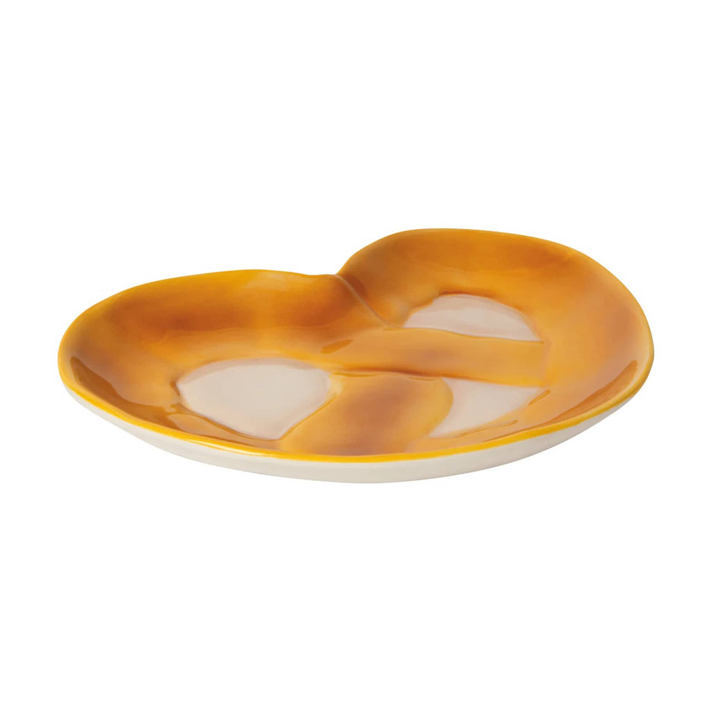 Ceramic pretzel shaped trinket or serving dish, side view on a white background.