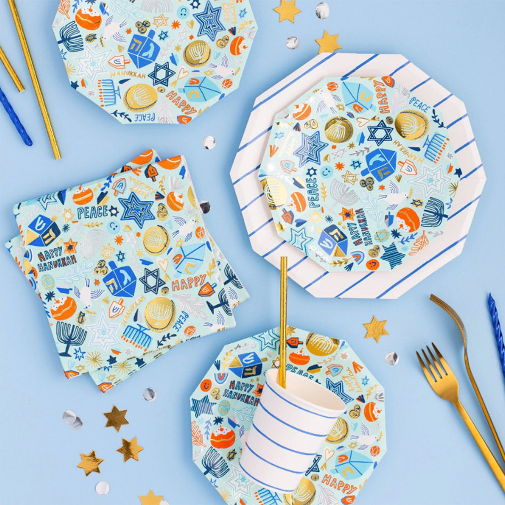 Daydream Society Festival of Lights small paper party plates and large napkins with Hanukkah themed illustrations on a light blue background in a party table setting.