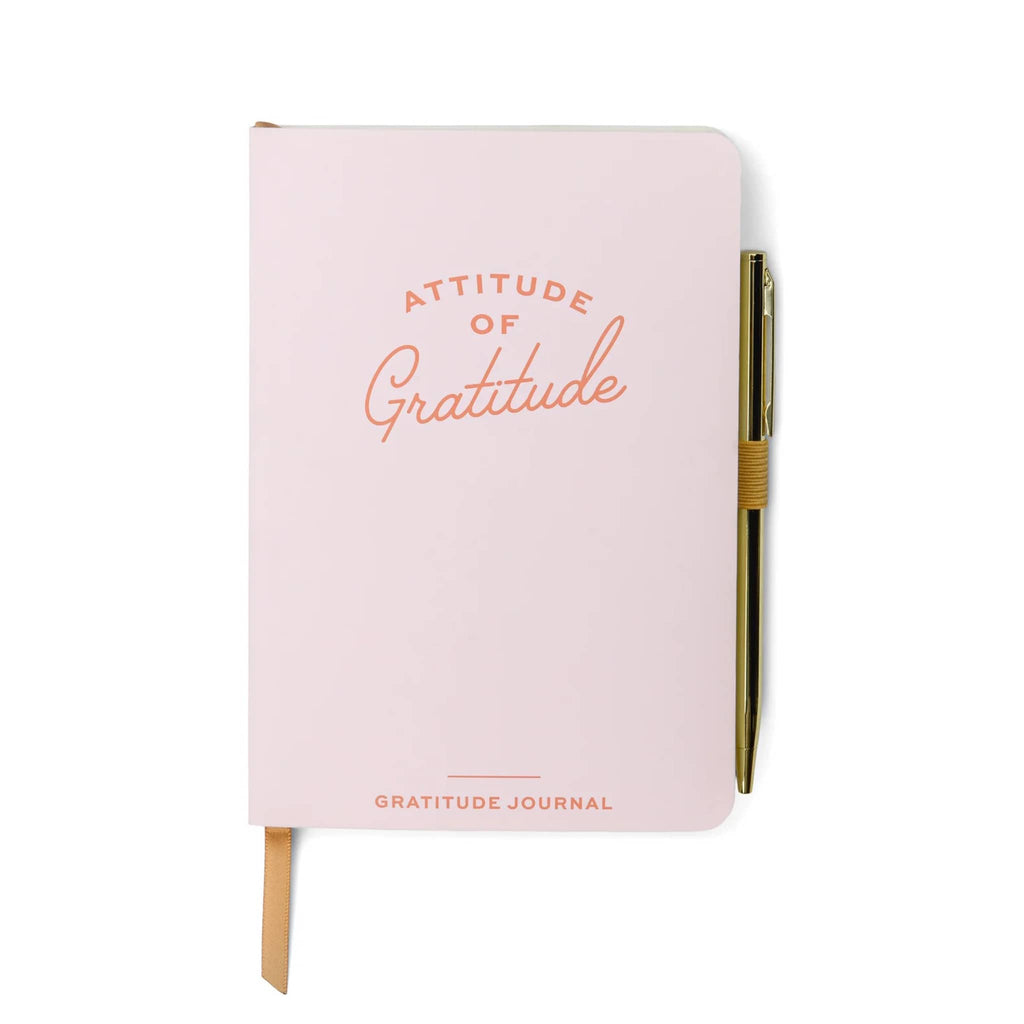 Designworks Ink pink softcover gratitude journal, front cover with "attitude of gratitude" in peach lettering and gold tone pen attached.