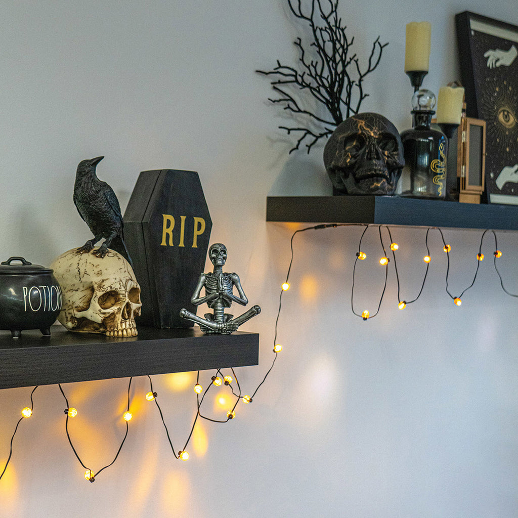 DM Merchandising Spooky Lites On-the-Vine Pumpkin Bulbs decorating wall shelves with Halloween decorations.