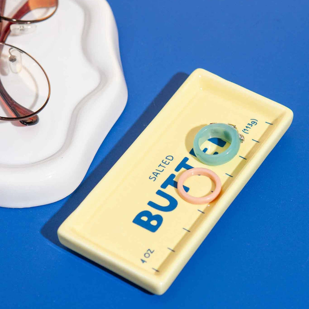Ceramic butter trinket tray with resin rings on a blue background.