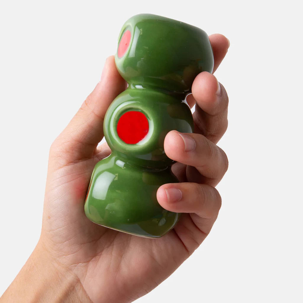 Hand holding a ceramic vase that looks like 3 stacked olives on a white background.