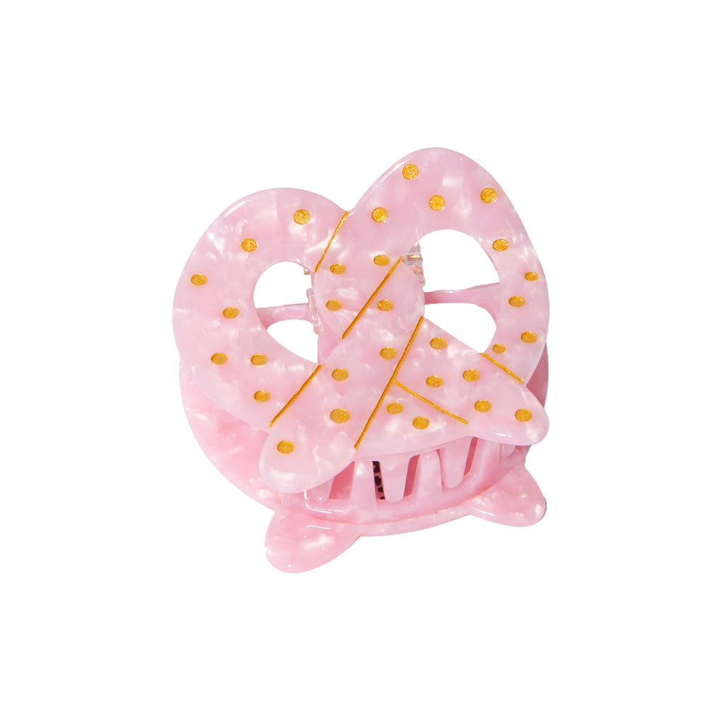 Pink pretzel hair claw with gold dots on a white background.