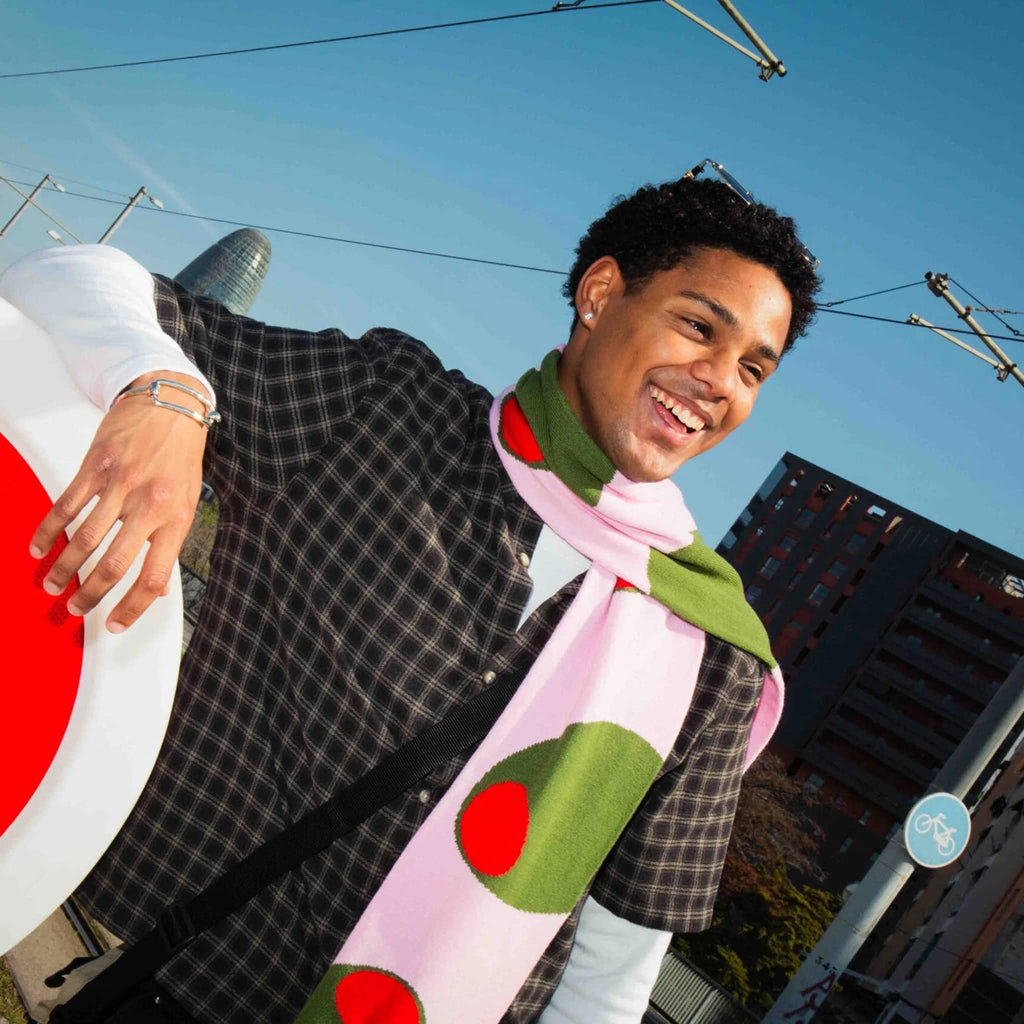 Person wearing a pink scarf with olives with city background.