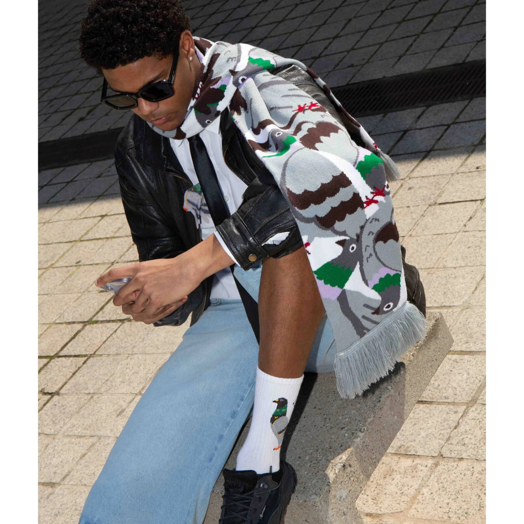 Person wearing a pigeon patterned scarf, black leather jacket, light blue jeans, and white socks with pigeon design.
