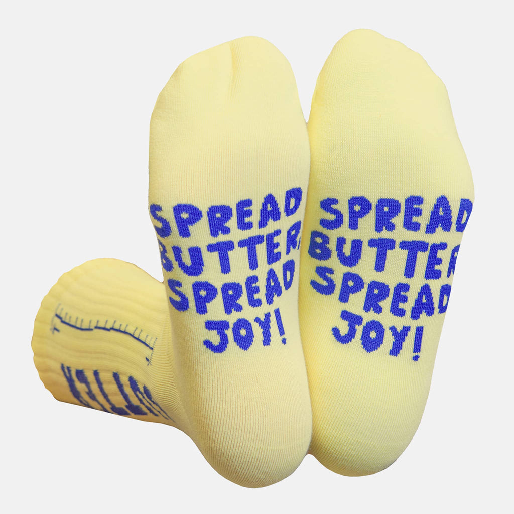 Yellow socks with blue text 'Spread Butter Spread Joy!' on the bottom, on a white background.