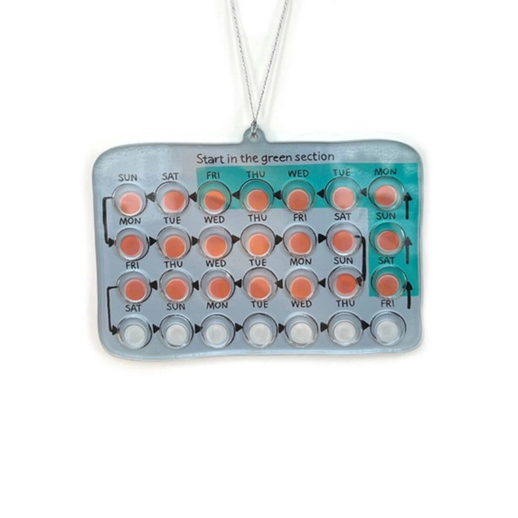 Acrylic birth control pill ornament with colored slots for each day of the week on a white background.