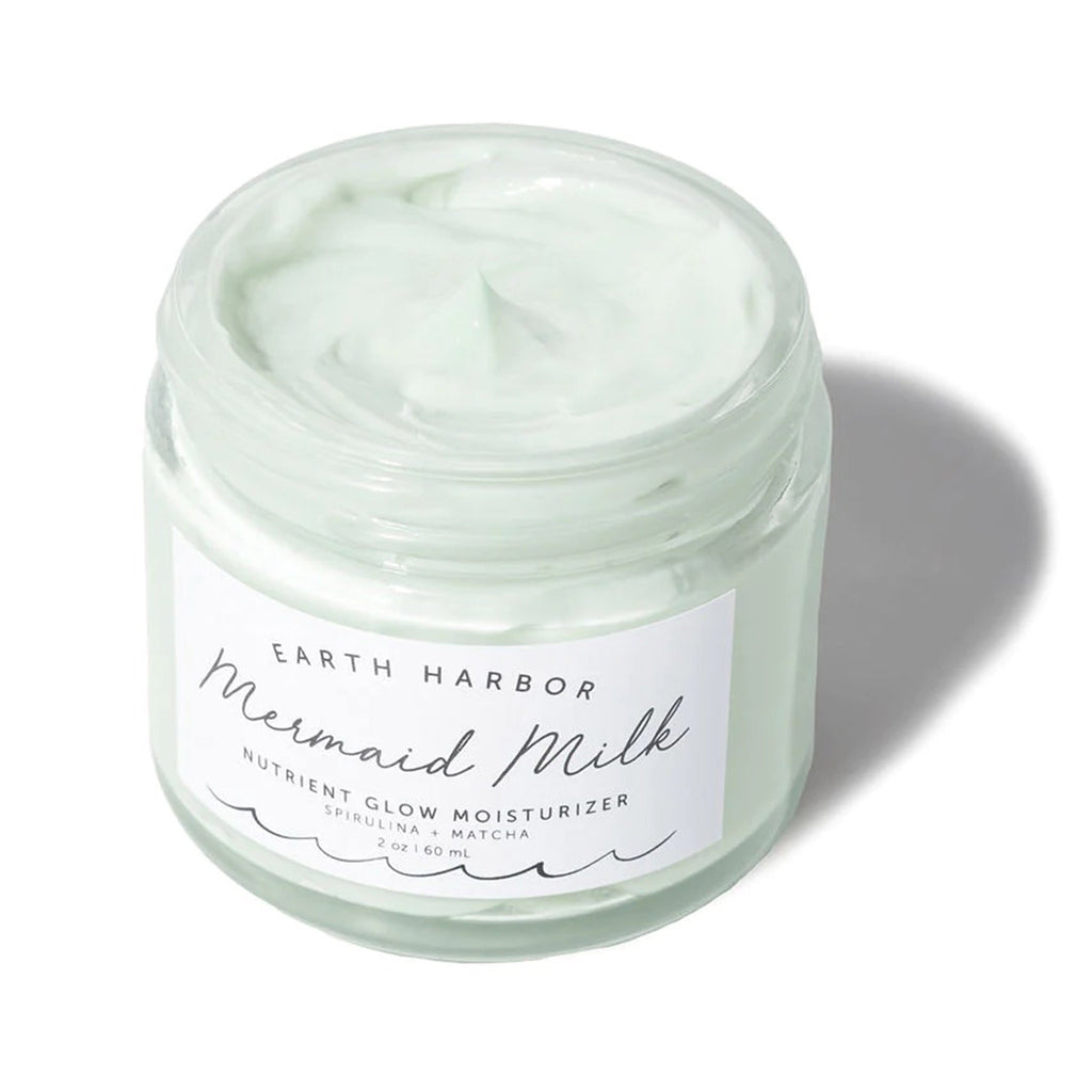 Earth Harbor Mermaid Milk Nutrient Glow Moisturizer with Spirulina and Matcha in glass jar, overhead view, lid off.