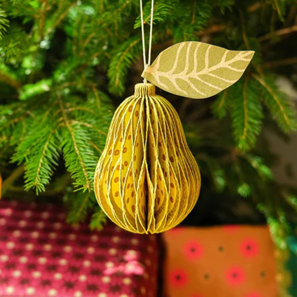 Decorative green pear-shaped honeycomb paper ornament with a leaf on a Christmas tree.