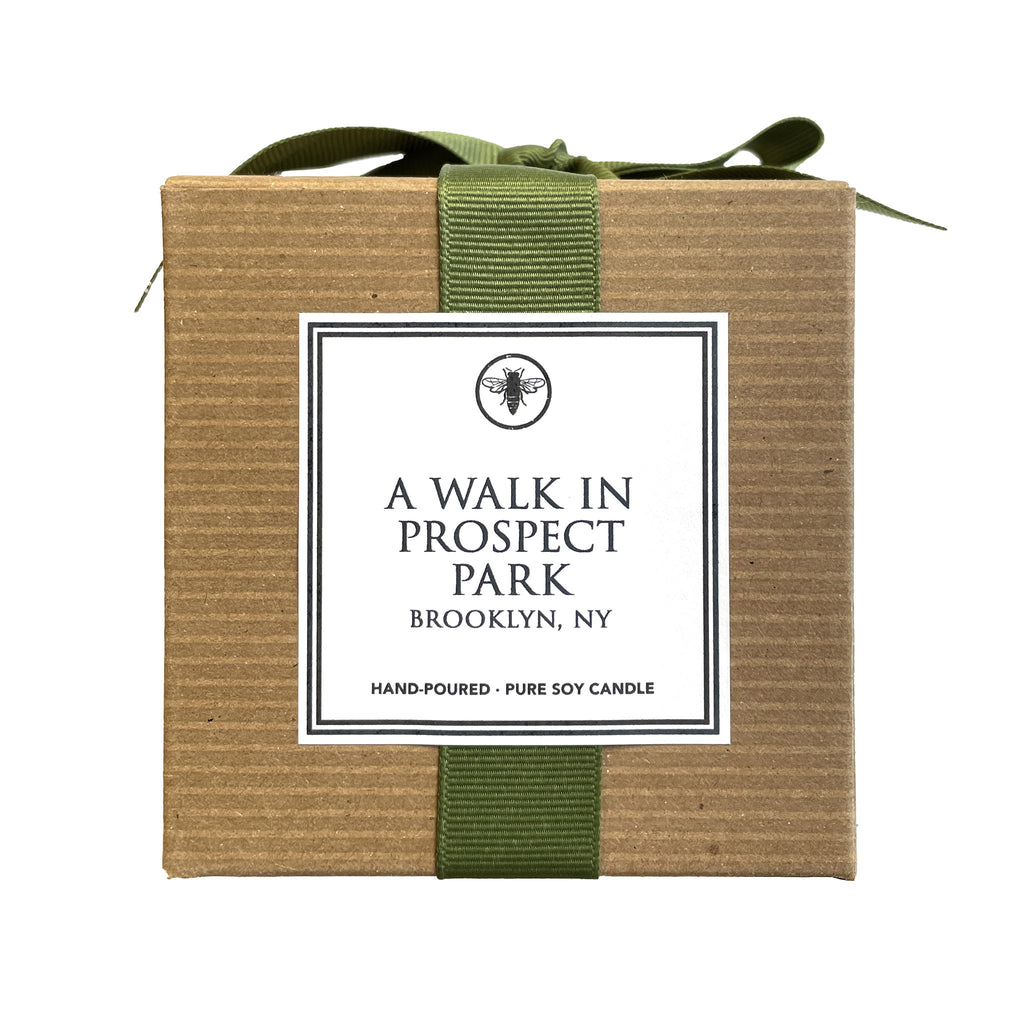 Ella B Candles A Walk in Prospect Park birchwood and evergreen bark scented soy wax candle in brown kraft gift box with green grosgrain ribbon bow and white label, front view.