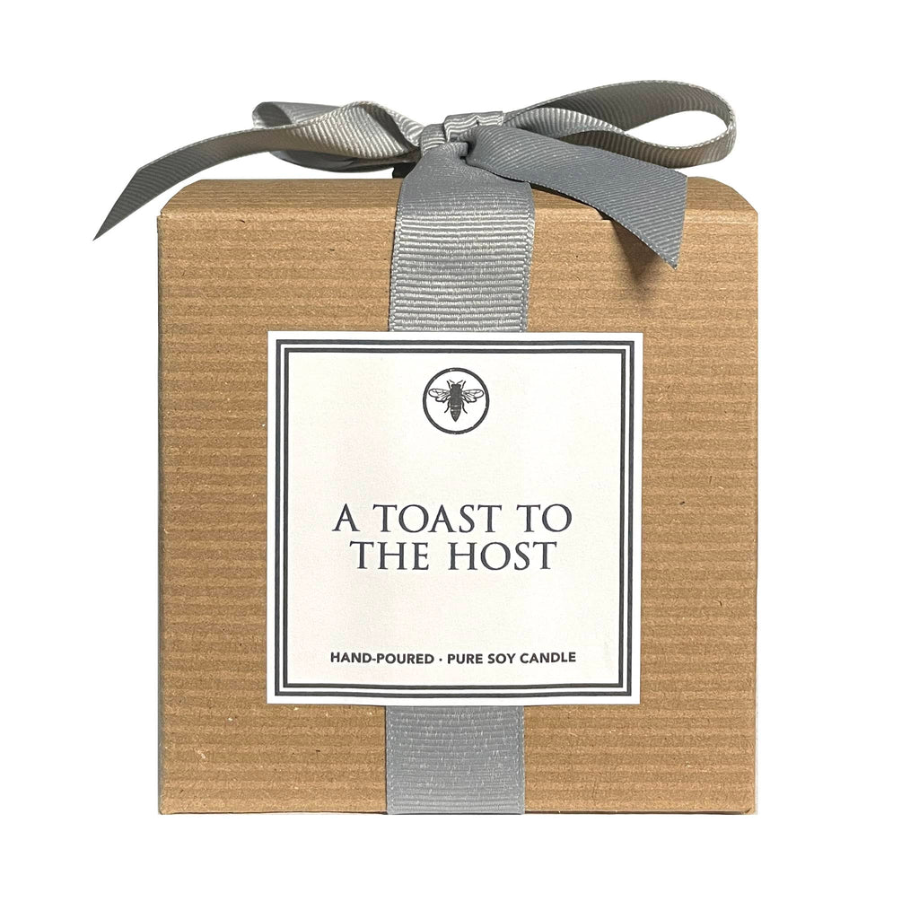 Ella B Candles "A Toast to the Host" white flower, citron and bergamot scented soy wax candle in brown kraft paper box with gray grosgrain ribbon, front view.