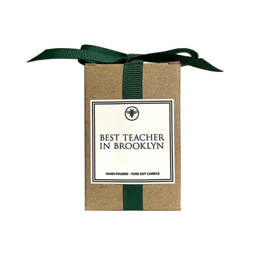 Ella B Candles scented soy wax votive candle in kraft box with forest green grosgrain ribbon bow, front view with white label and "best teacher in brooklyn" in black lettering with black border.