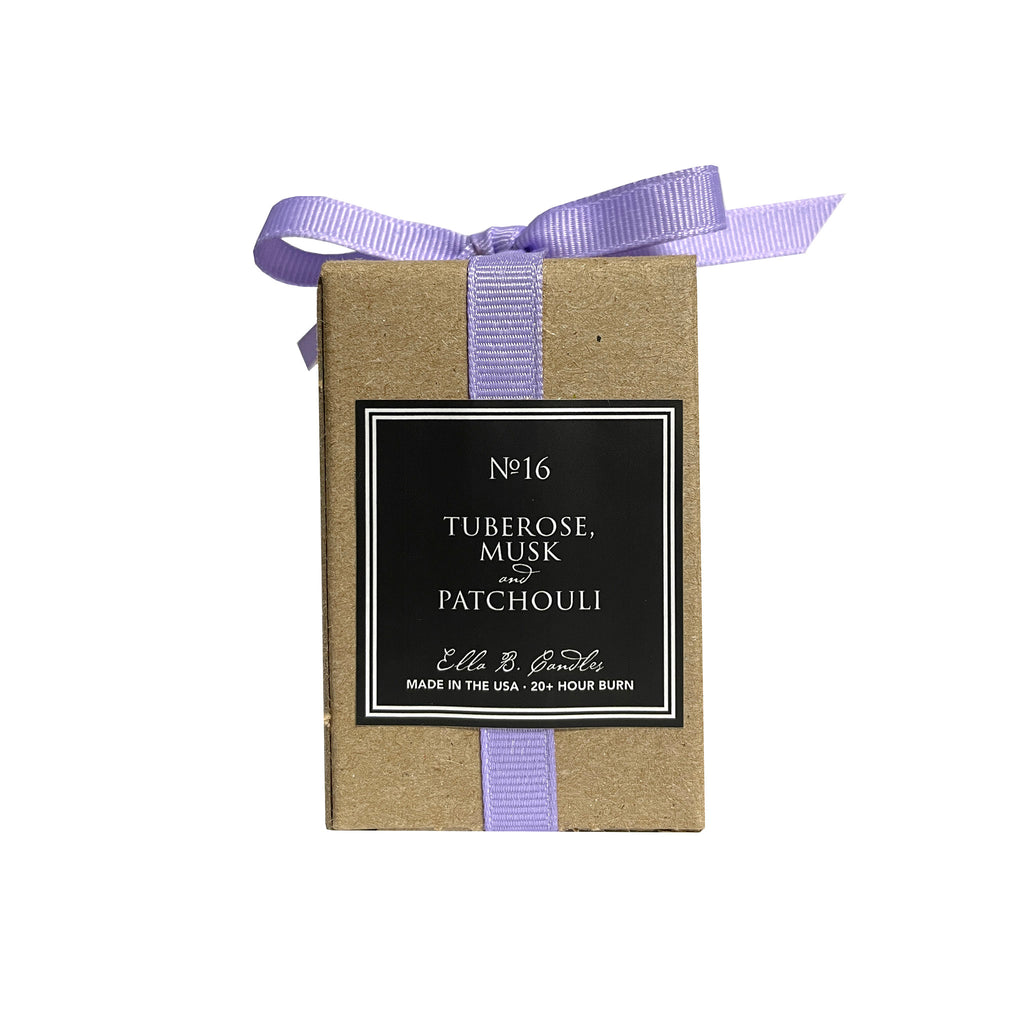 Ella B Candles scented soy wax votive candle in kraft box with lavender grosgrain ribbon bow, back view with black label with scent notes in white lettering with white border.