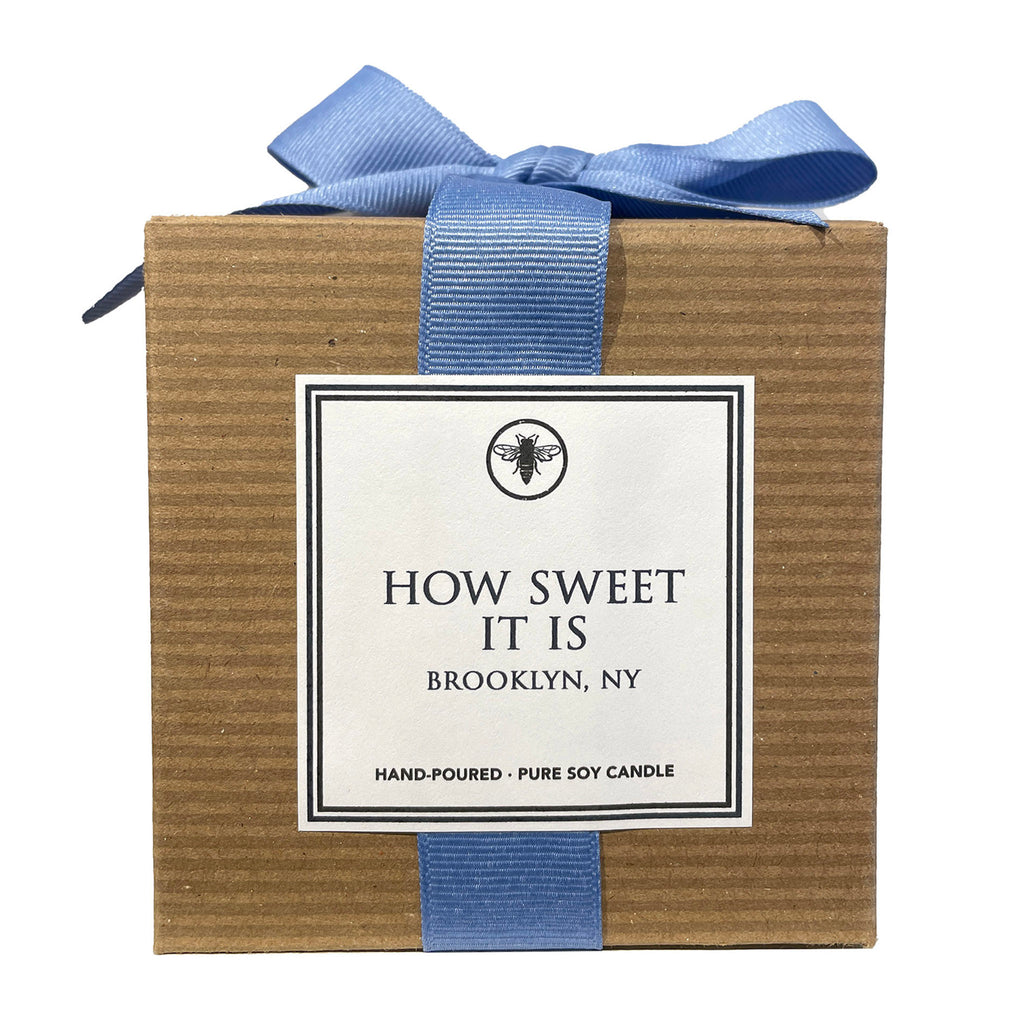 Ella B Candles "How Sweet It Is" pear and redwood scented soy wax candle in brown kraft paper box with bluebell blue grosgrain ribbon, front view.