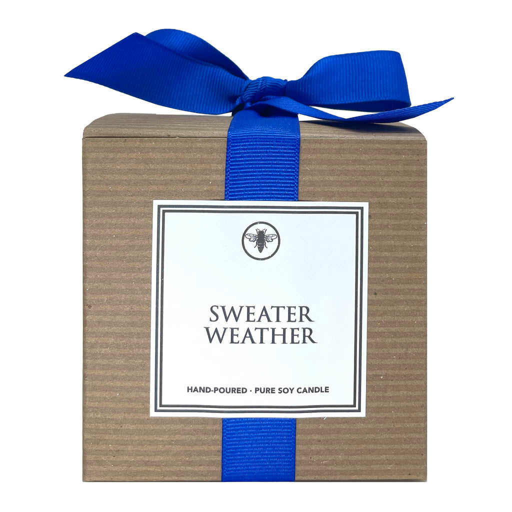 Ella B Candles Sweater Weather sandalwood and cashmere scented soy wax candle in kraft box packaging with blue grosgrain bow, front view.