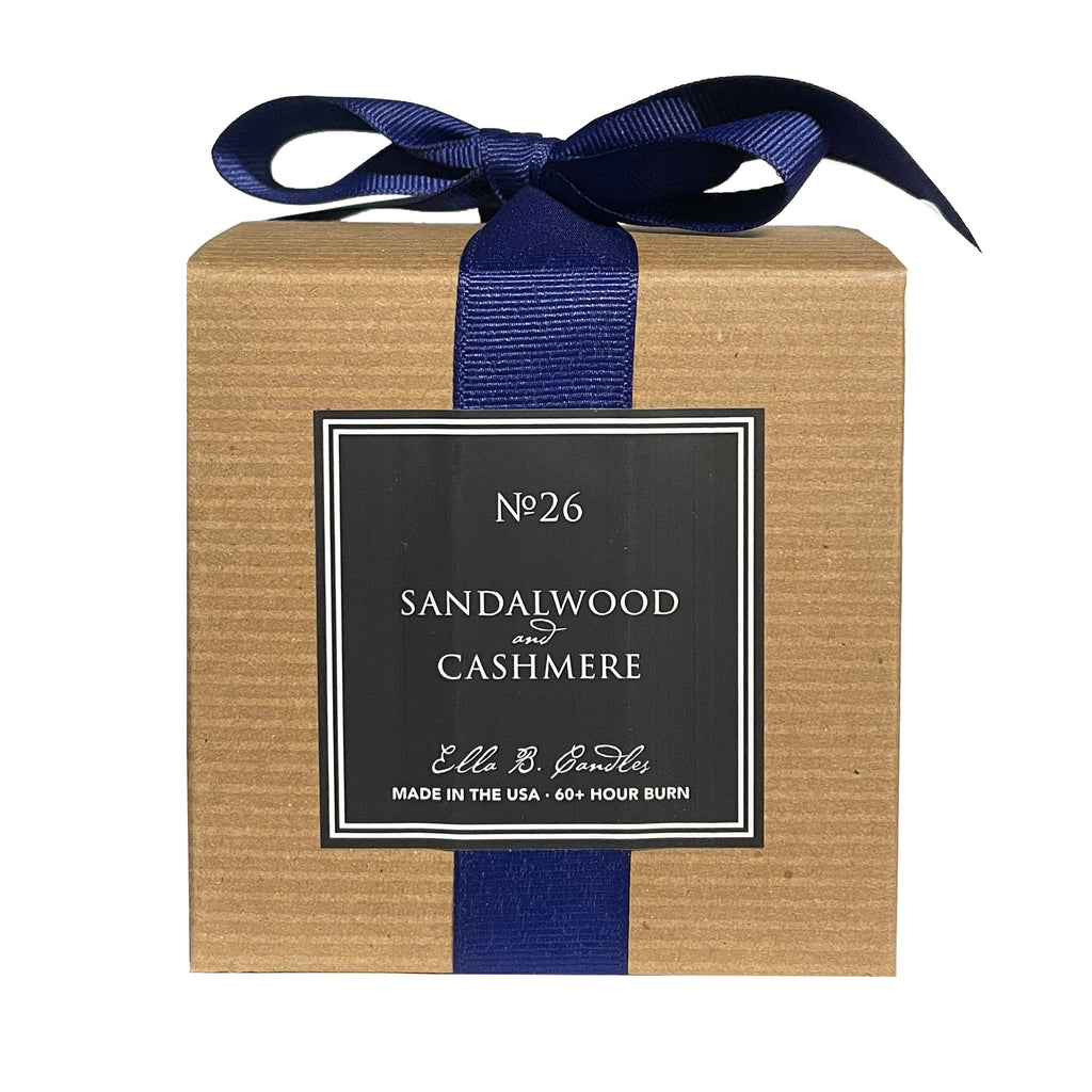Ella B Candles "There's No Place Like Home" sandalwood and cashmere scented soy wax candle in brown kraft paper box with navy blue grosgrain ribbon, back view.