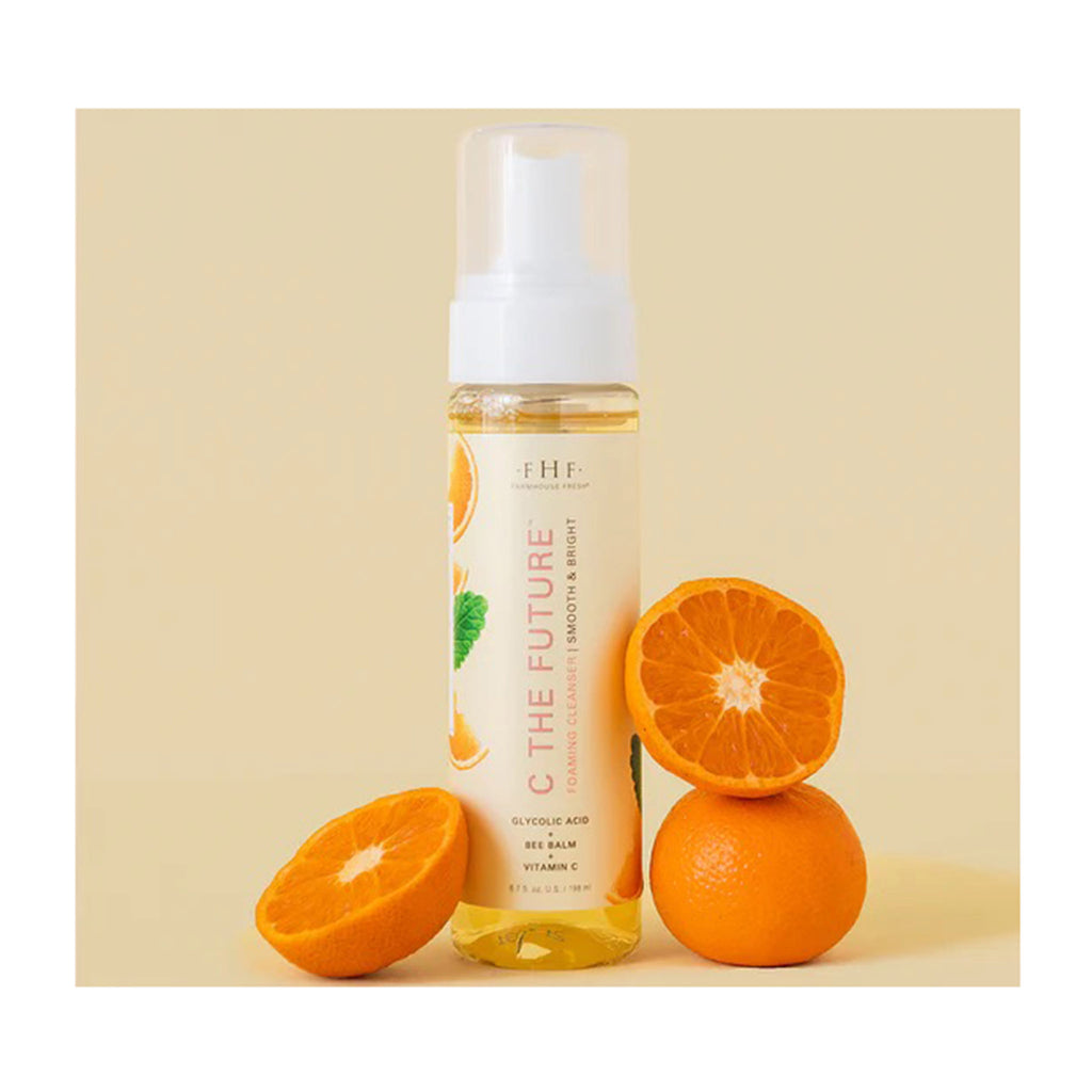FarmHouse Fresh C the Future Foaming Facial Cleanser in bottle packaging with cut oranges on a yellow background.