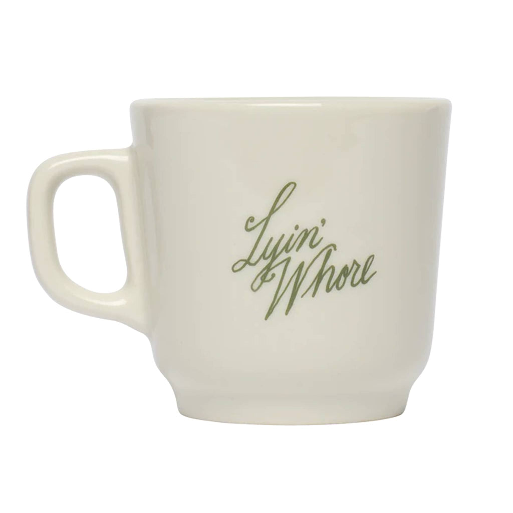 White mug with "Lyin' Whore" in green text, on a white background.