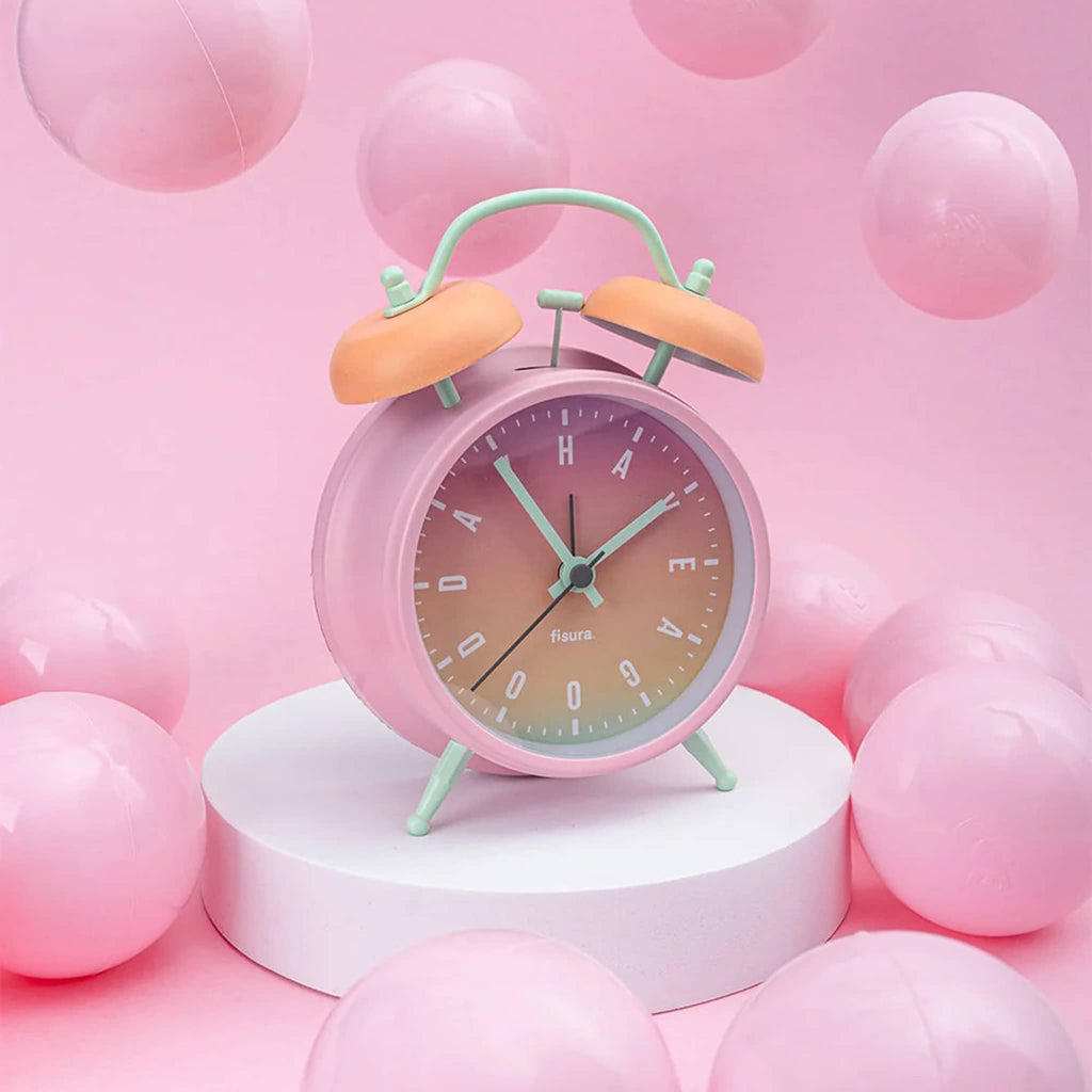 Pastel-colored alarm clock on a pink  background with pink balloons.