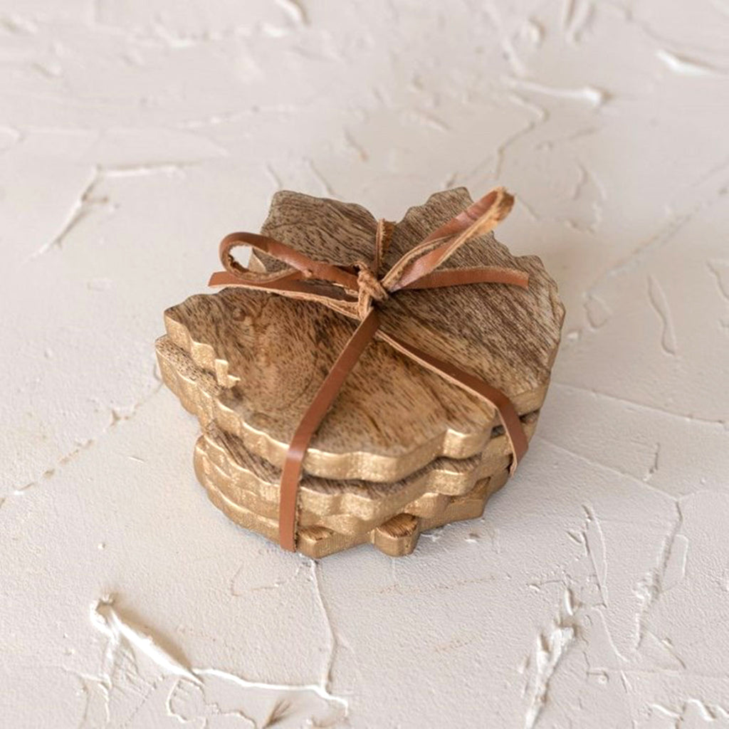 Foreside mango wood hansel maple leaf-shaped coasters, set of 4 tied with leather string, overhead view on textured background.