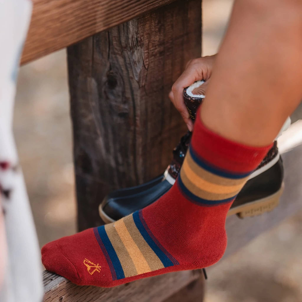 Person wearing red striped socks with a wooden bench in the background.