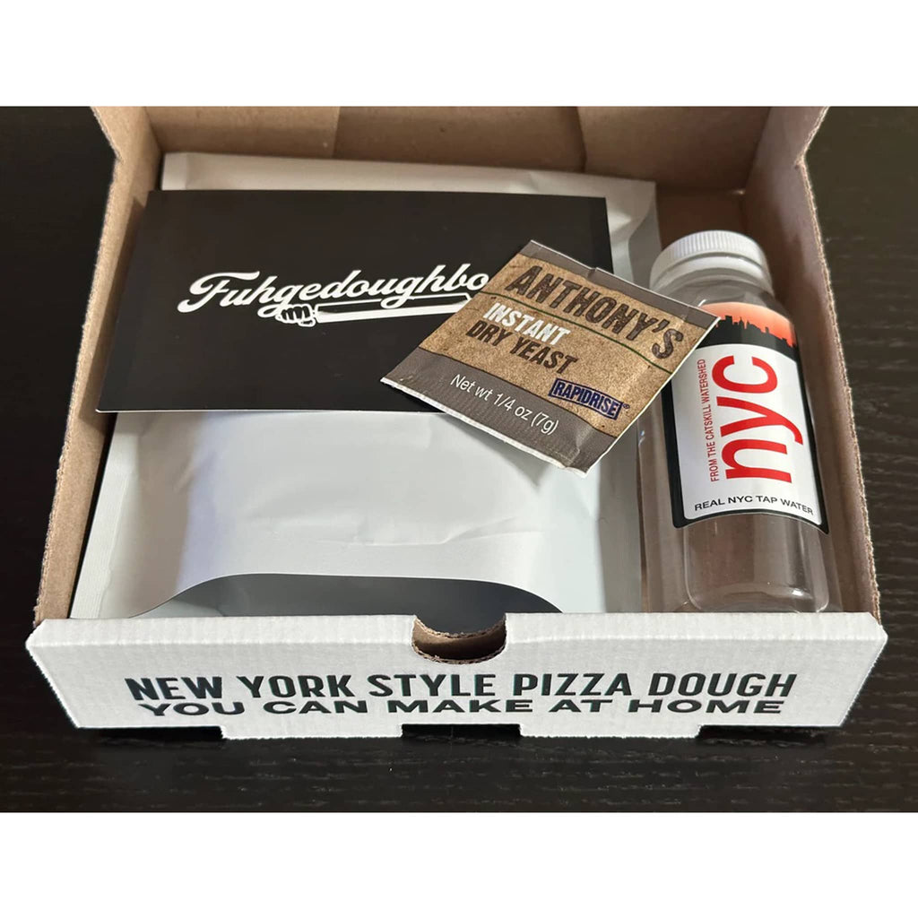 Box containing New York-style pizza dough, yeast, and a bottle of nyc tap water with visible branding.