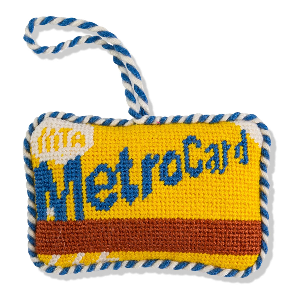 Blue and yellow MetroCard needlepoint ornament with a hanging loop on a white background.