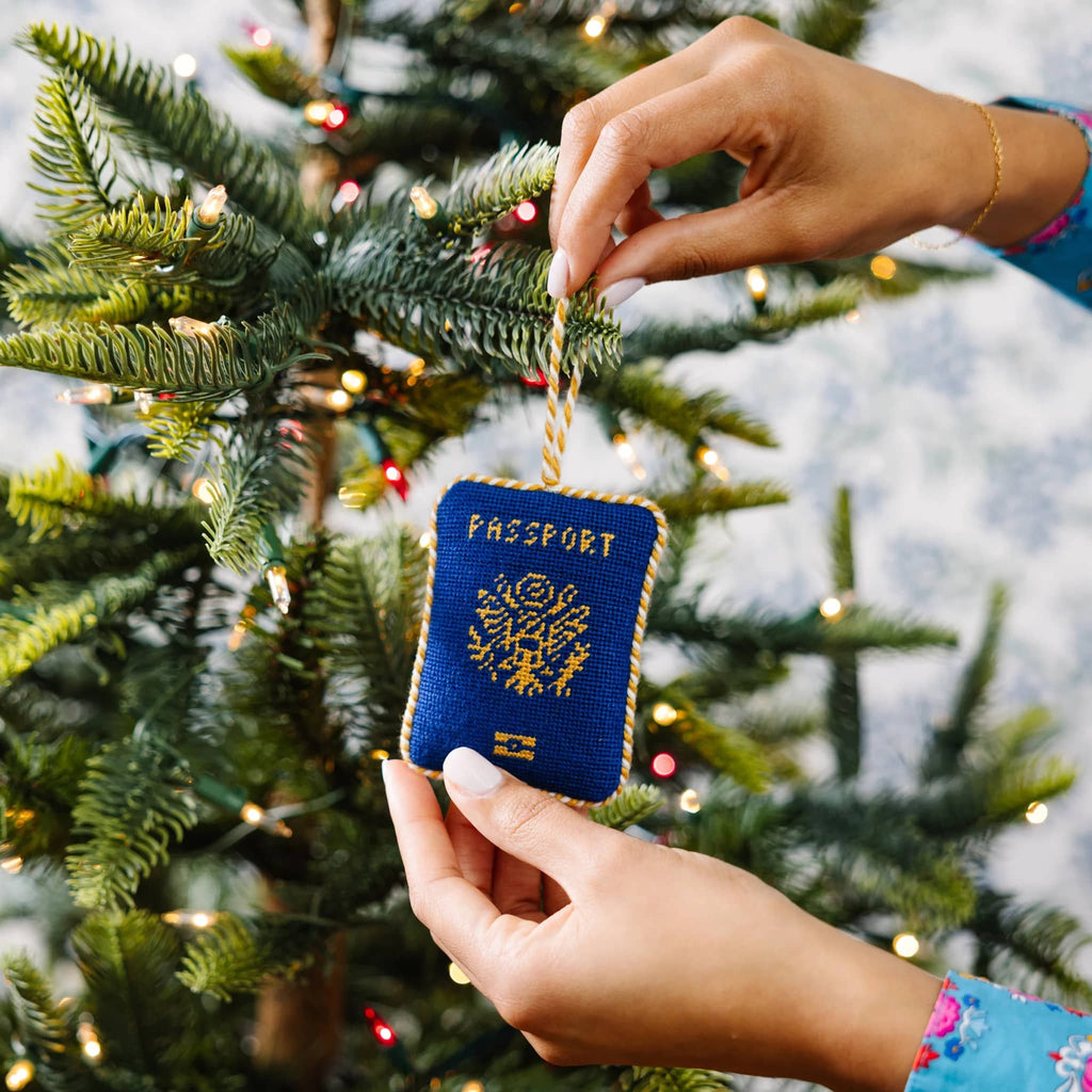 Passport-shaped ornament being hung on a Christmas tree.