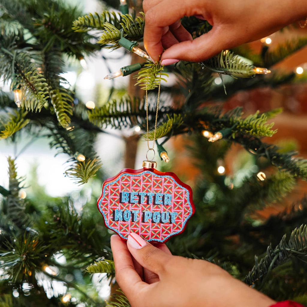 Person hanging a Christmas ornament with 'Better Not Pour' text on a decorated tree.